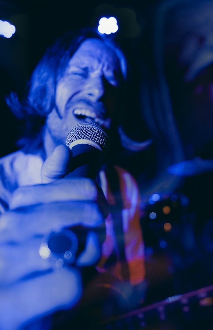 A singer passionately performing with a microphone, bathed in blue lighting.